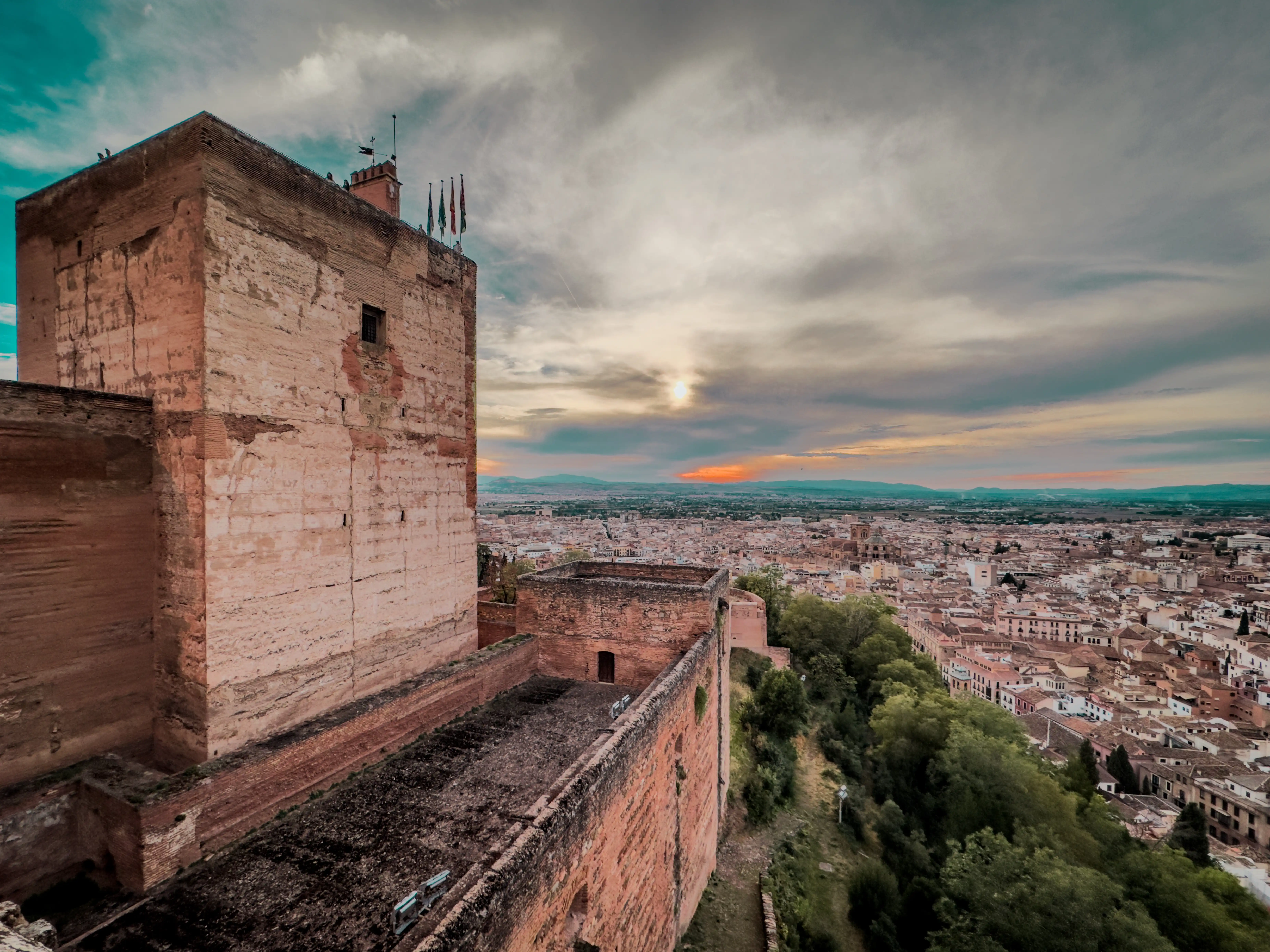 Alhambra walls and city view beneath a dramatic cloudy sky.