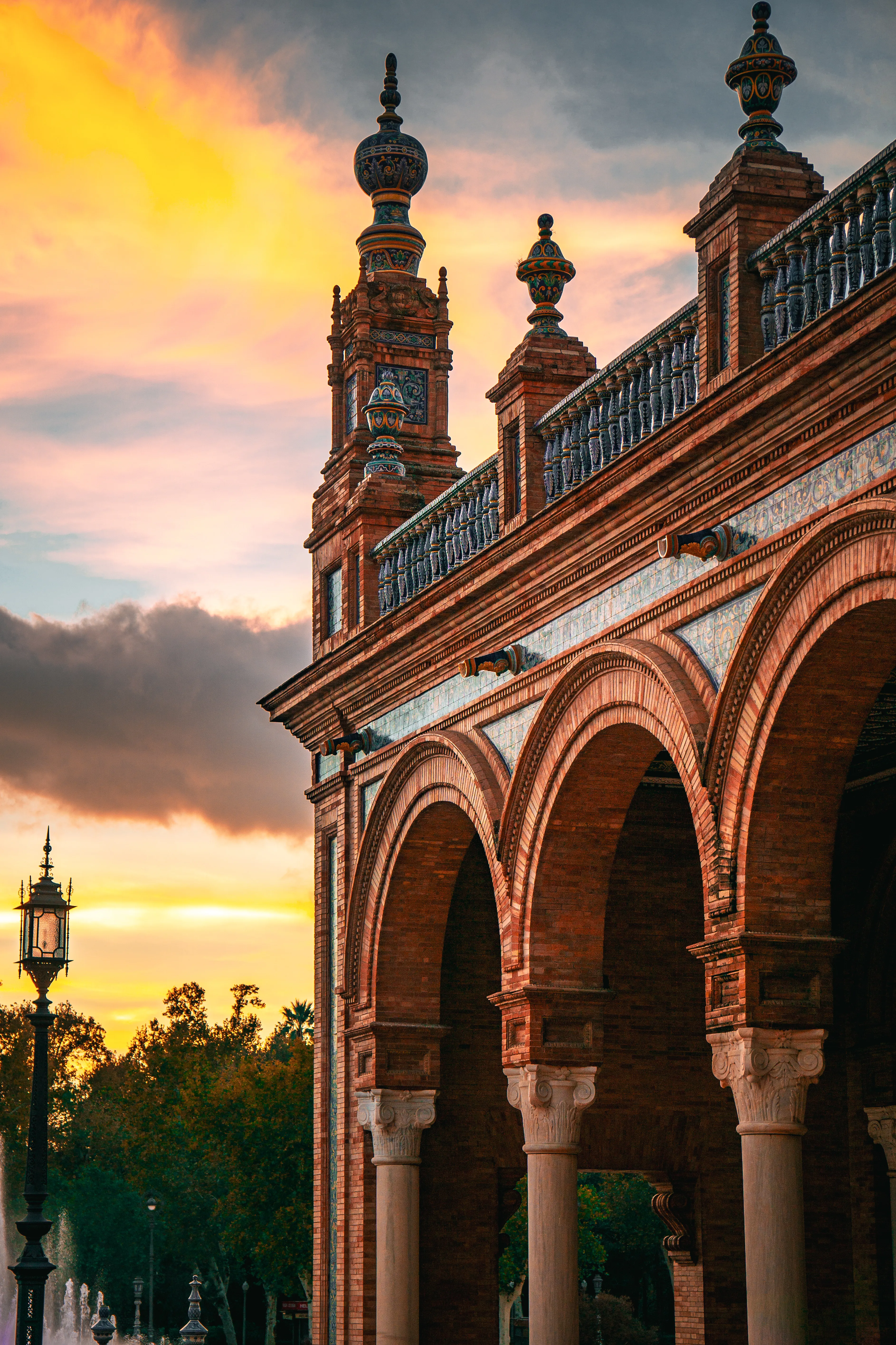 Brick arcade and towers lit by sunset with a dramatic sky.