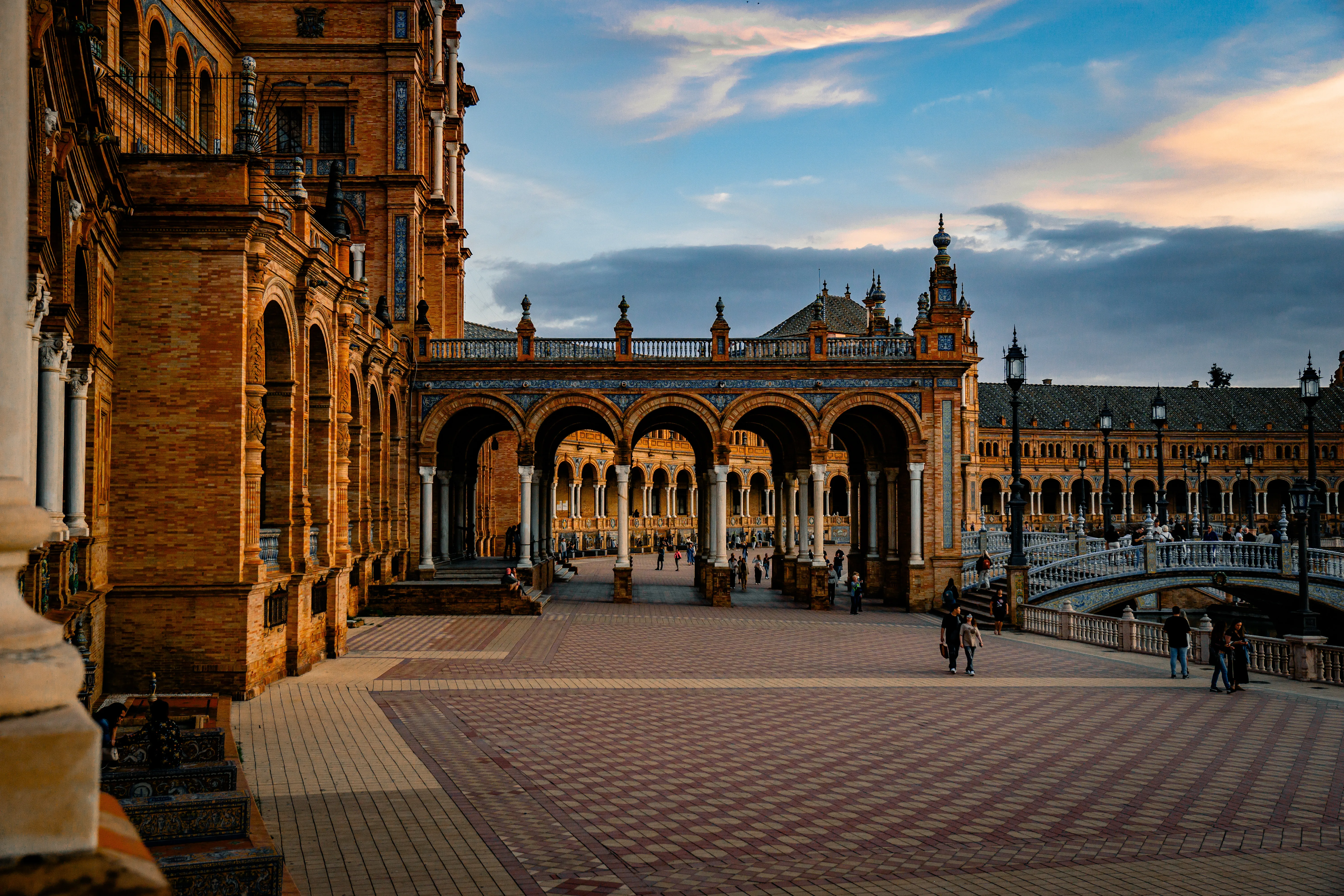 Arcades and tiled plaza at Plaza de Espana in warm evening light.