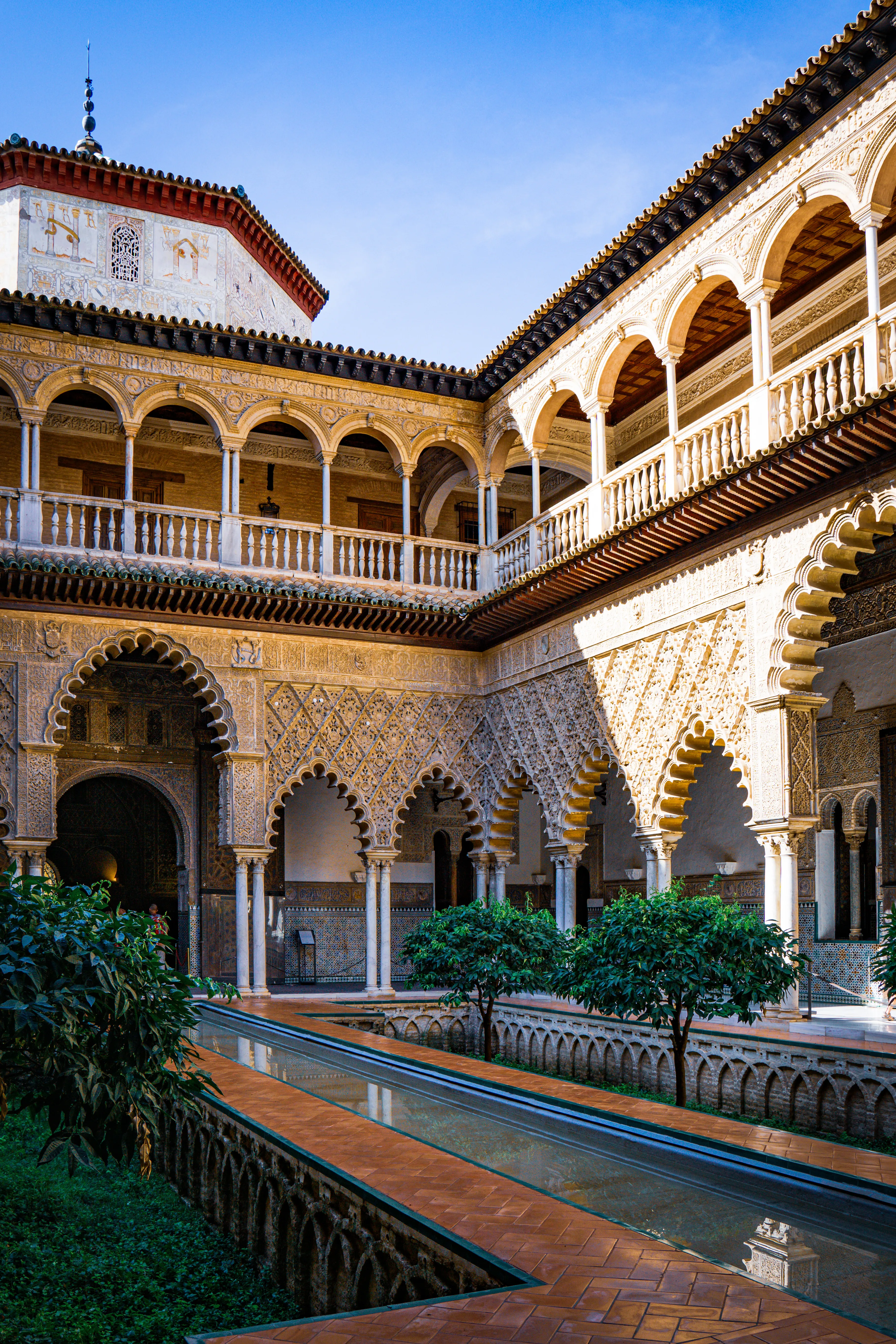 Arched courtyard with tiled walls, columns, and a narrow reflecting channel.