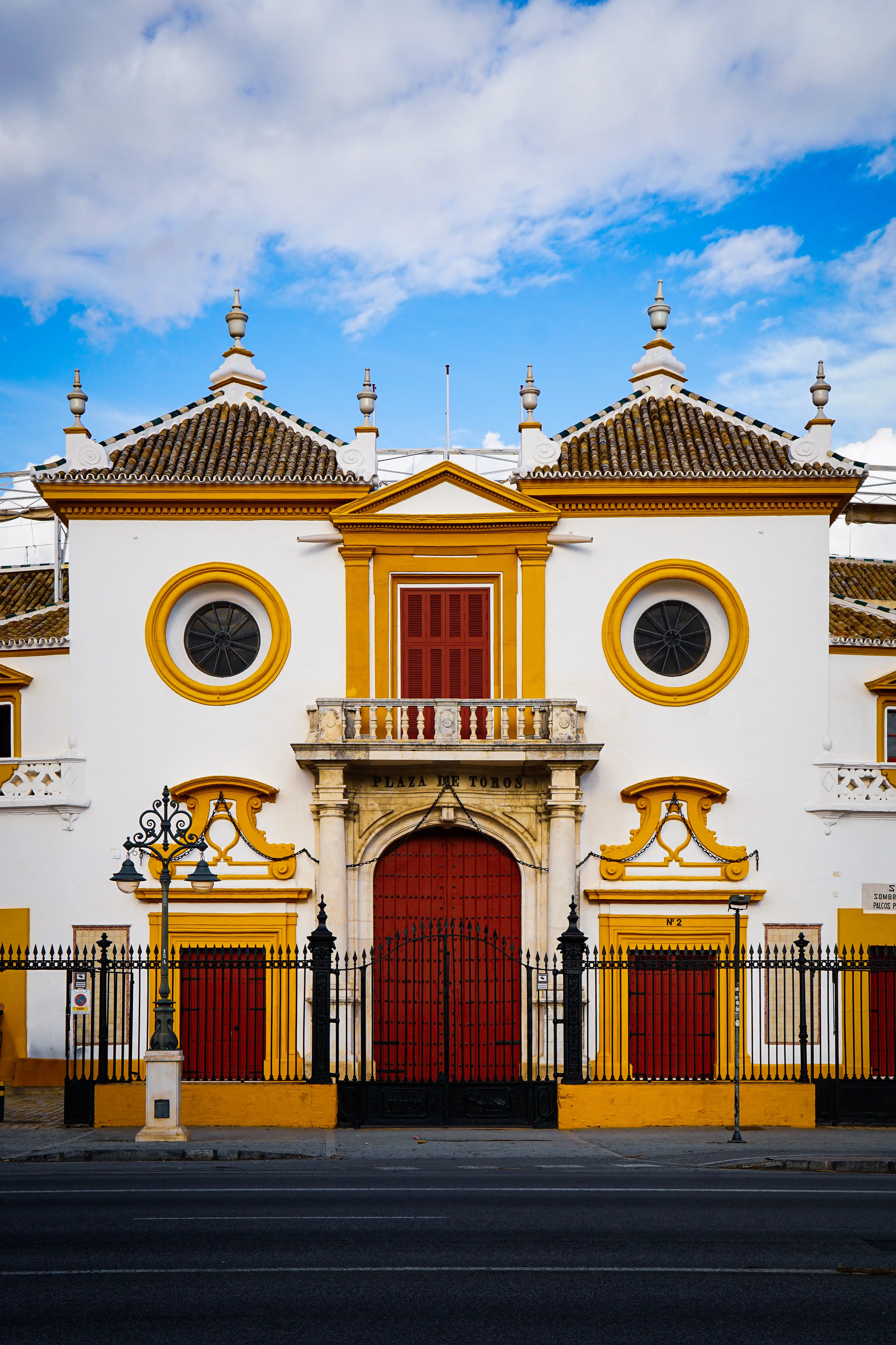 Yellow and white church facade with red doors and round windows.