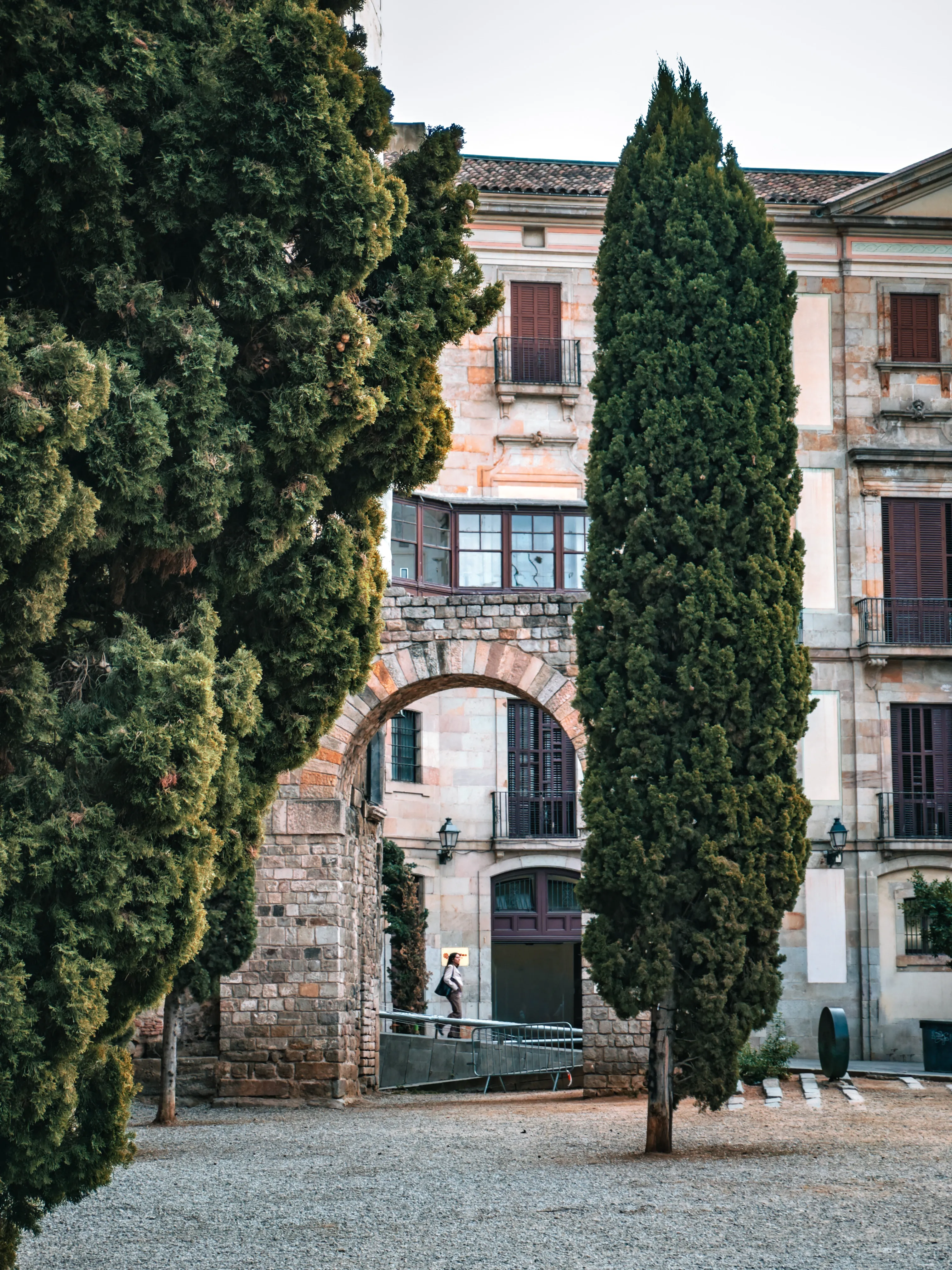 Old stone gate and cypress tree beside a quiet courtyard.
