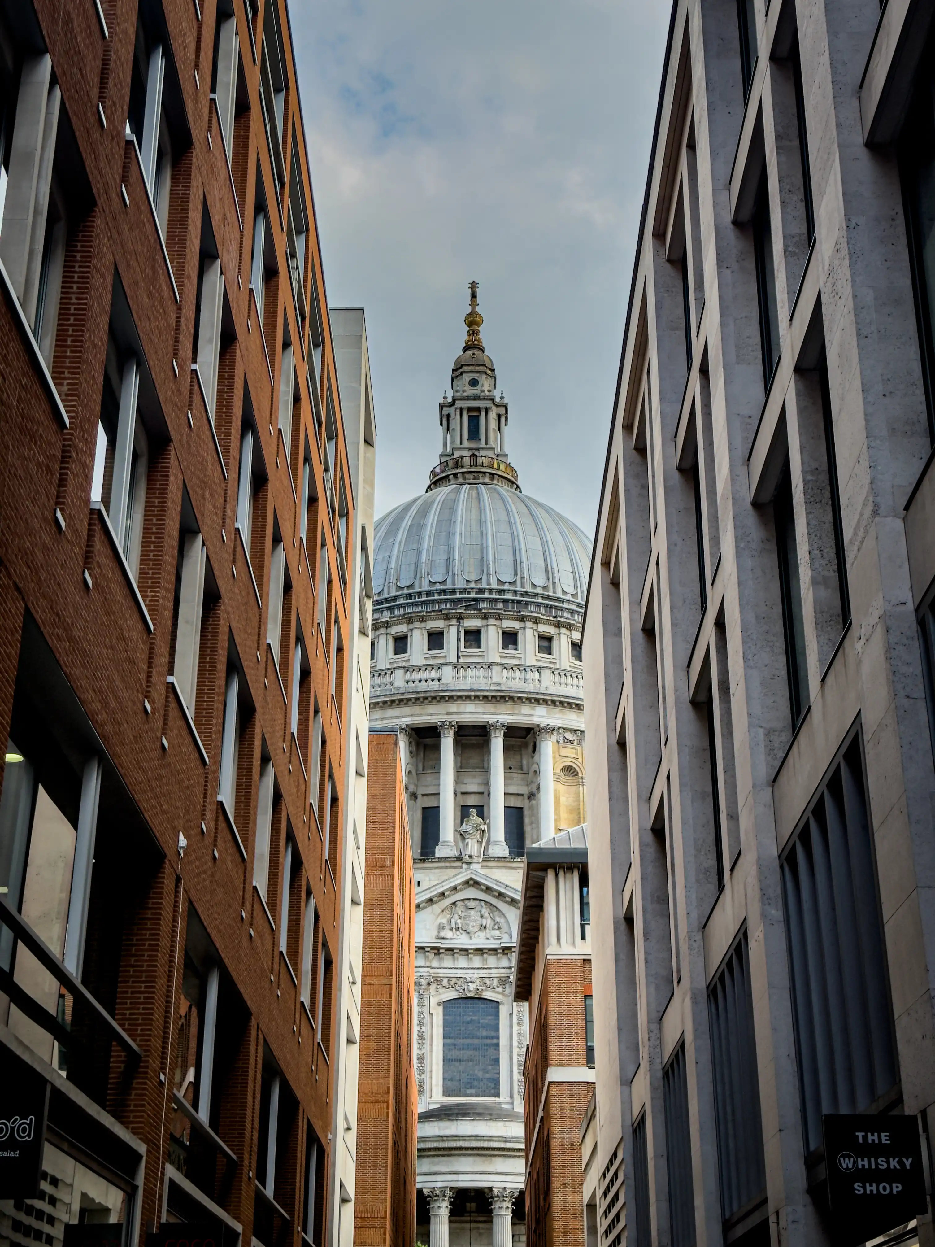 St. Paul's Cathedral dome seen between narrow London buildings.