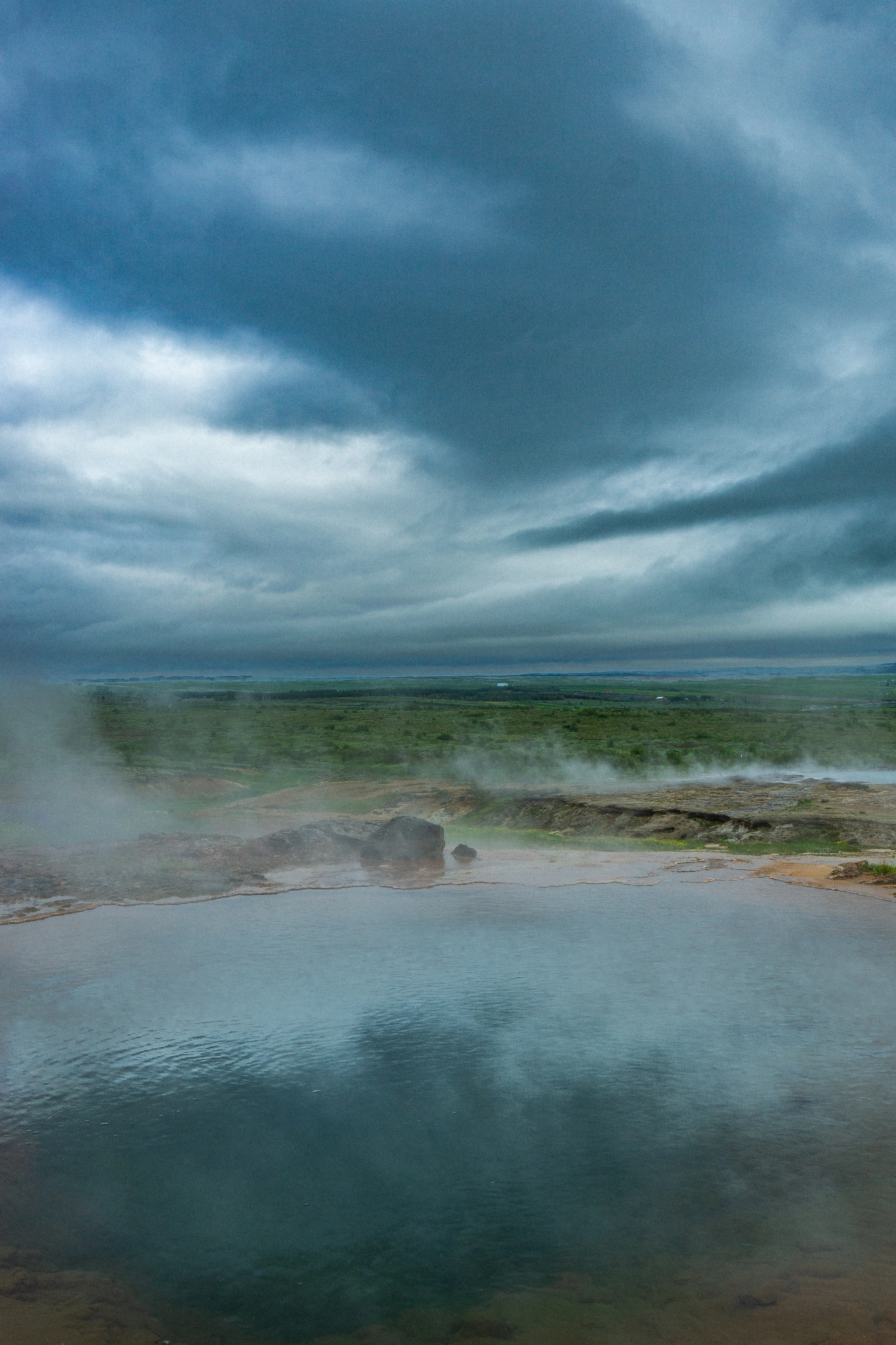 Blue geothermal pool steaming beneath a cloudy Icelandic sky.