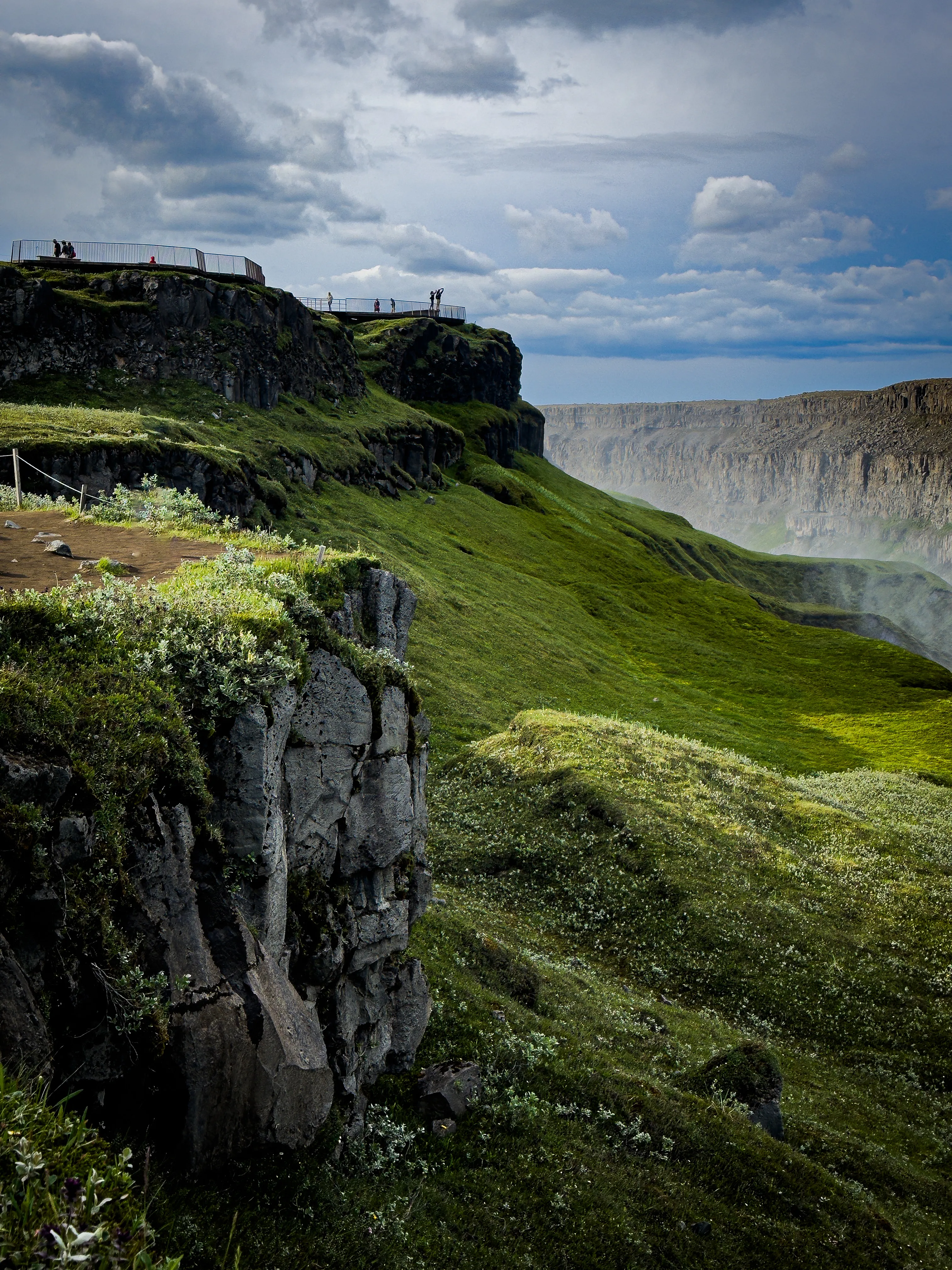 Green Icelandic cliffs with a waterfall dropping toward the coast.