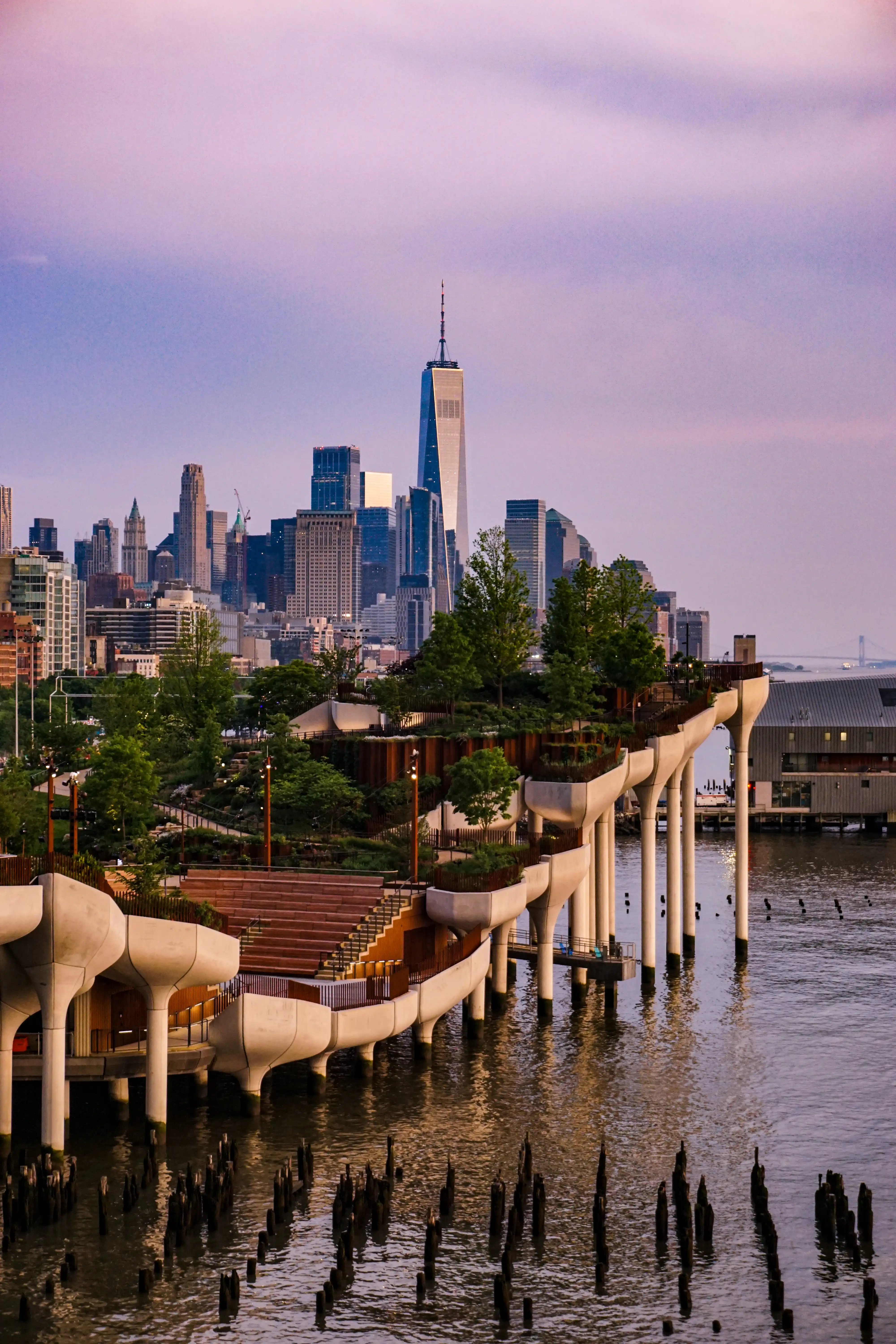 Manhattan skyline and waterfront under pink and violet evening light.