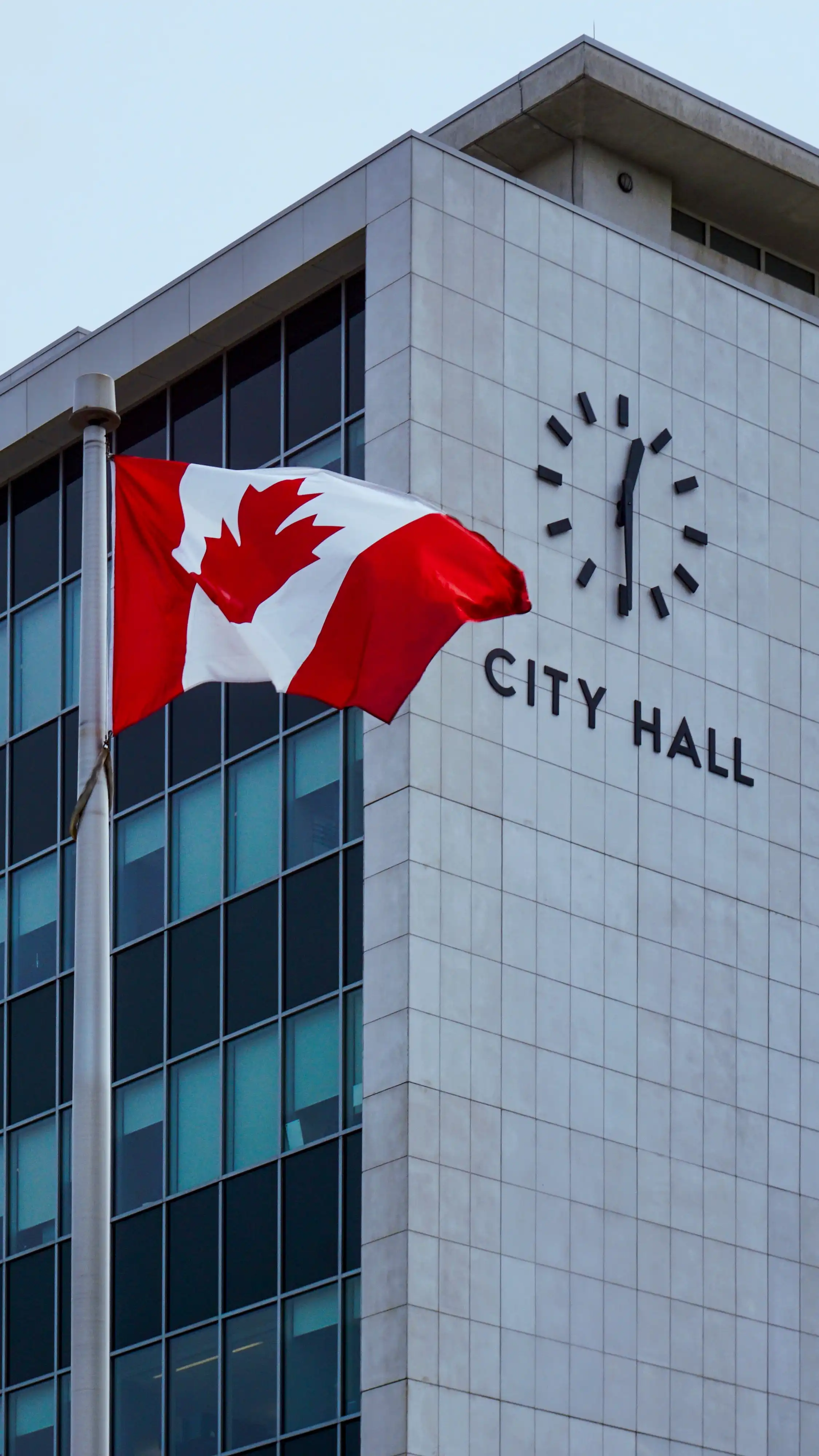 Canadian flag flying in front of a city hall building.